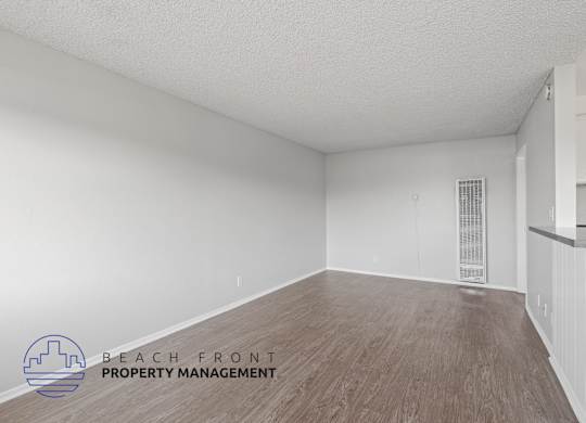the spacious living room with wood flooring and white walls