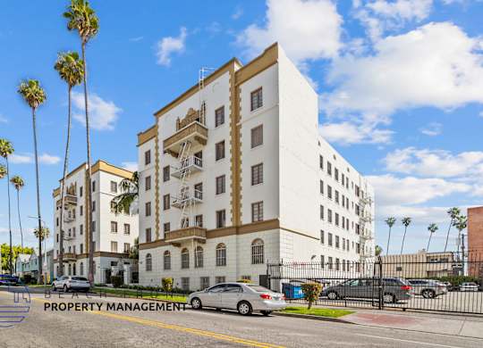 A white building with a sign that says Property Management on the bottom left.