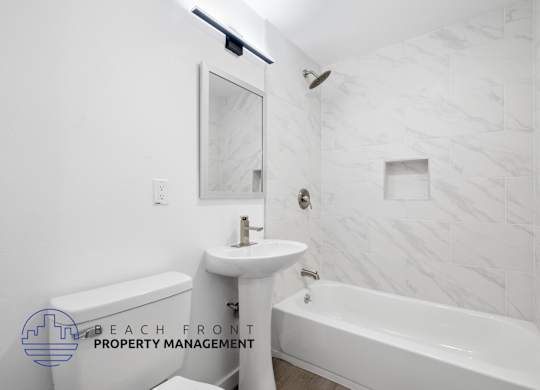 A white bathroom with a marble tile wall and a bathtub.
