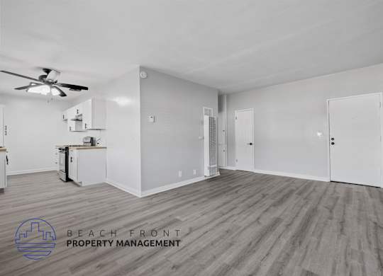 A spacious room with a ceiling fan and wooden flooring.