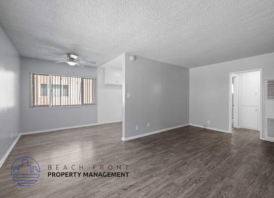 the spacious living room with hardwood flooring and a ceiling fan