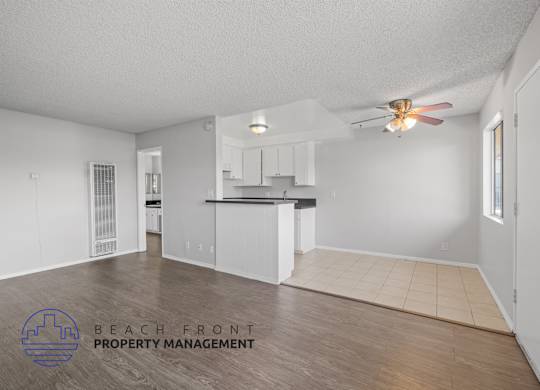 an empty living room and kitchen with a ceiling fan