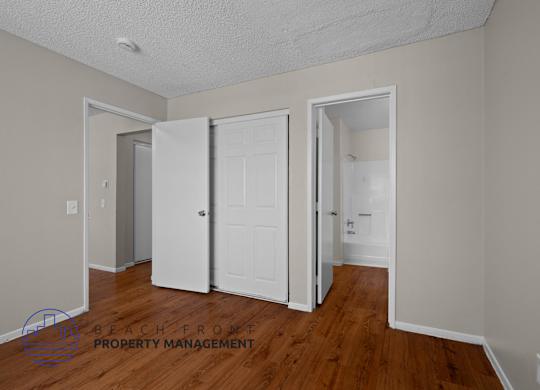 A room with a white door and a wooden floor.