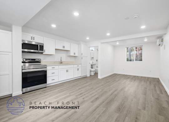 A spacious kitchen with white cabinets and a wooden floor.