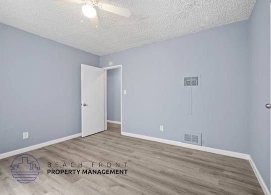 A room with a ceiling fan and a doorway leading to another room.