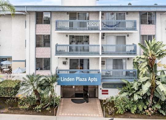 Linden Plaza Apts is a white apartment complex with a blue sign in front.