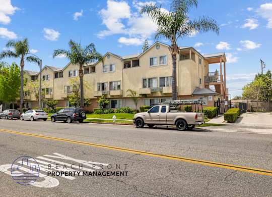 A beachfront property management logo is visible on the street in front of a row of houses.