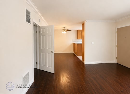 A room with a white door and wooden floors.