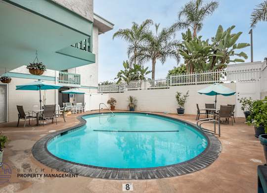 A pool surrounded by chairs and umbrellas with a sign that says