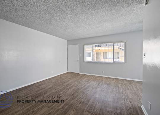 the living room of an apartment with wood flooring and a window