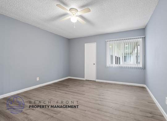 A room with a ceiling fan and a window with blinds.