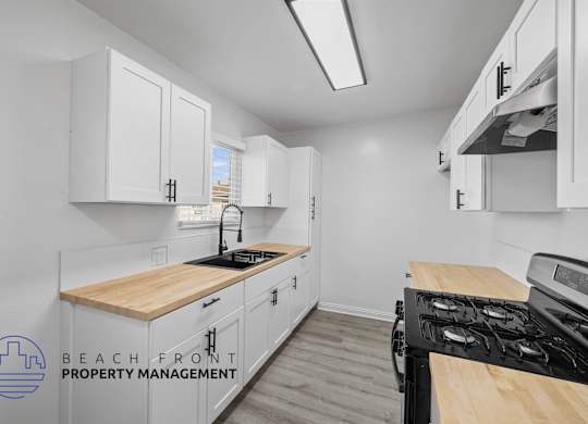 A kitchen with white cabinets and a wooden countertop.