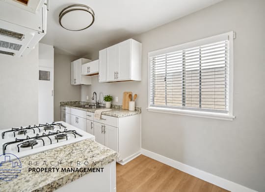 A kitchen with a white stove top oven and white cabinets.