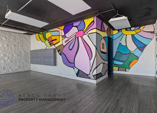 A colorful mural on the wall of a room with wooden flooring and a logo for Beach Front Property Management.