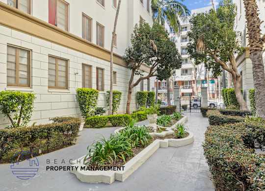 A well-maintained garden pathway with a variety of plants and trees.