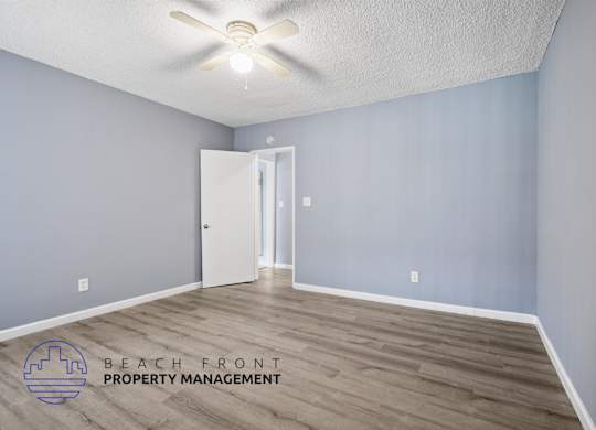 A room with a ceiling fan and a door leading to another room.