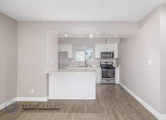A kitchen with a white island and wooden floors.