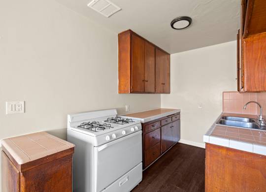 A kitchen with a white stove and wooden cabinets.
