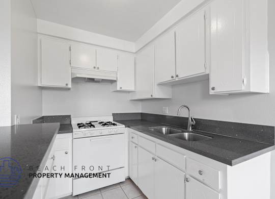 a white kitchen with white cabinets and black counter tops