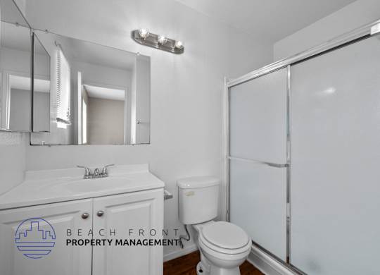 A white bathroom with a toilet, sink, and mirror.