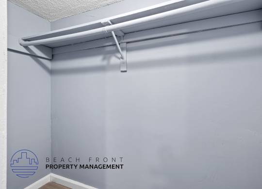 A white shelf with a white rod and a white hook on it.