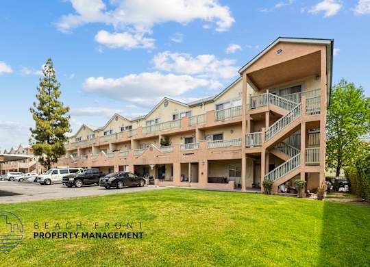 A multi-story apartment complex with a parking lot in front.