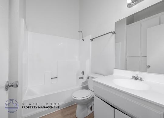 A white bathroom with a toilet, sink, and bathtub.
