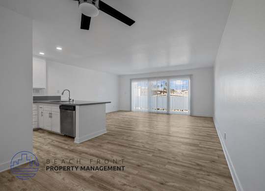 A spacious room with a kitchen area and a ceiling fan.