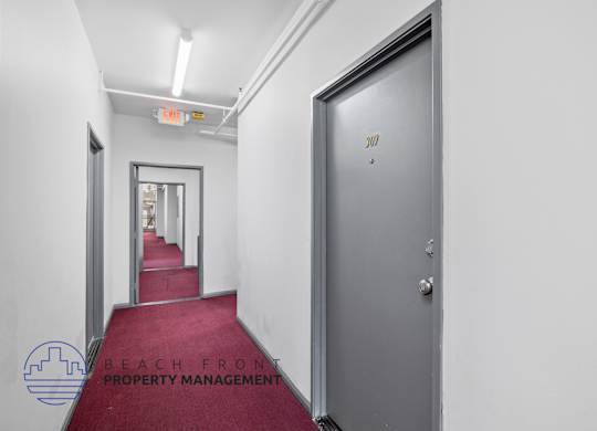 A hallway with a red carpet and a door on the right.