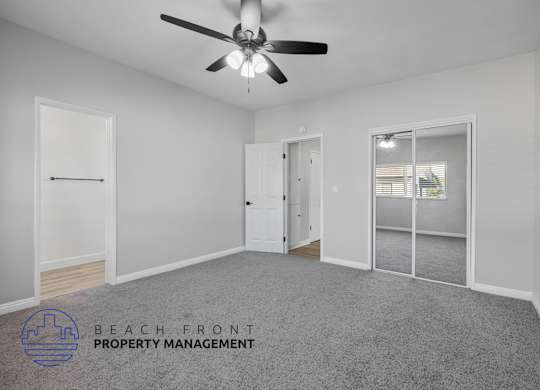 A spacious room with a ceiling fan and a logo for Beach Front Property Management.