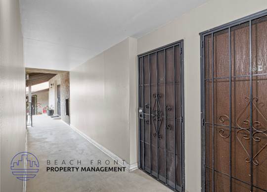 A hallway with a metal gate on the right and a wooden gate on the left.
