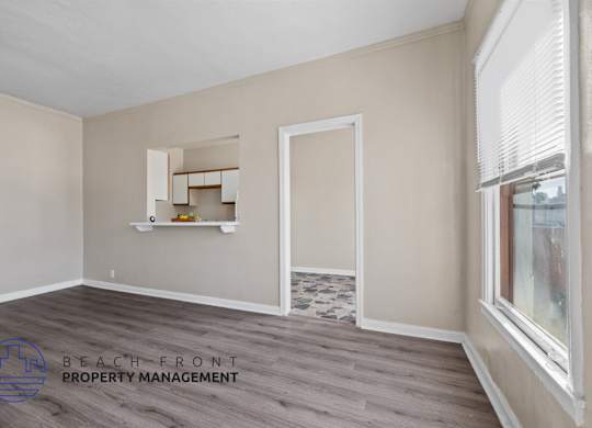 A room with a window and a shelf with a logo of Beach Front Property Management.