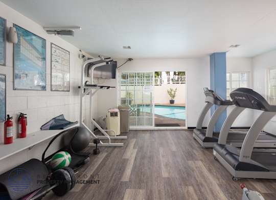 A gym with treadmills, weights, and exercise equipment.