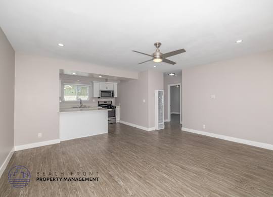 A spacious room with a ceiling fan and wooden flooring.