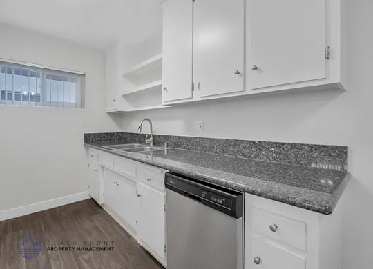 A kitchen with white cabinets and a granite countertop.