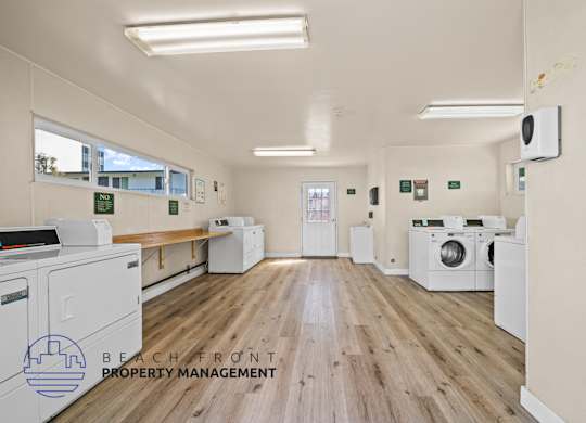 A laundry room with washers and dryers and a sign that says Beachfront Property Management.