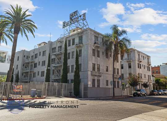 a building on the corner of a street with palm trees