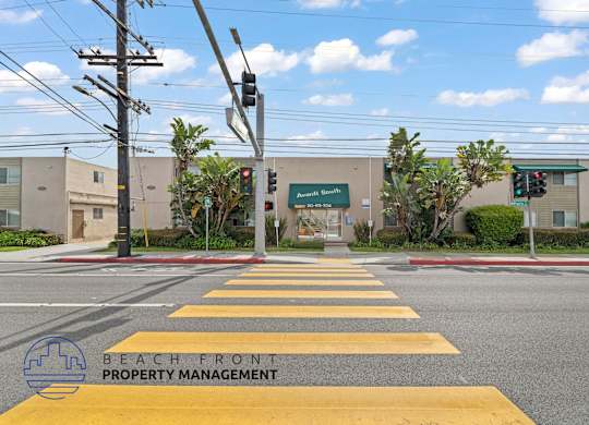 A street view with a yellow crosswalk and a sign for Beachfront Property Management.