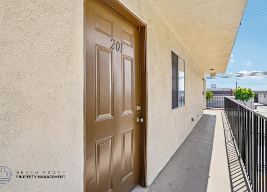 A brown door with the number 201 on it is on the left side of a balcony.