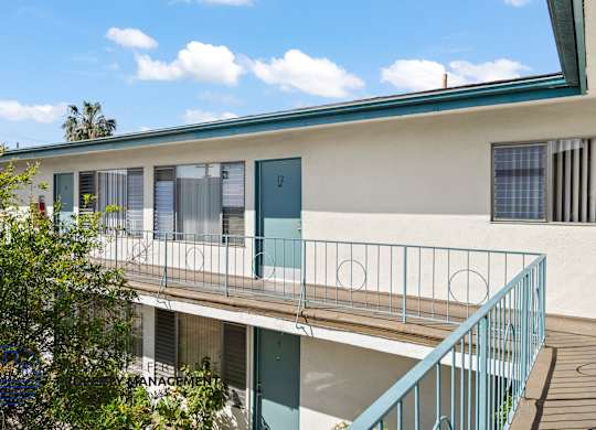 A white building with a blue door and a balcony.