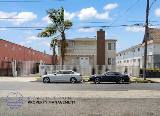 Two cars parked in front of a building with a palm tree and a sign that says