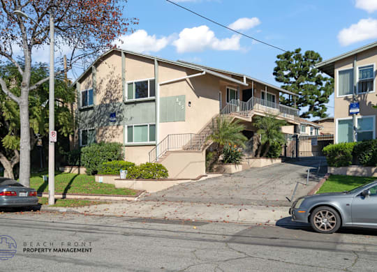 A car is parked on the street in front of a two-story apartment building.