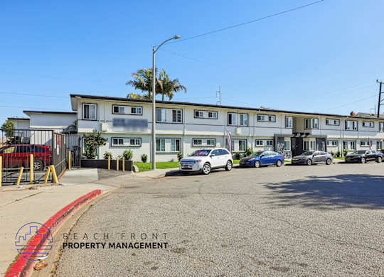 A parking lot with cars and a building with the words Beach Front Property Management.