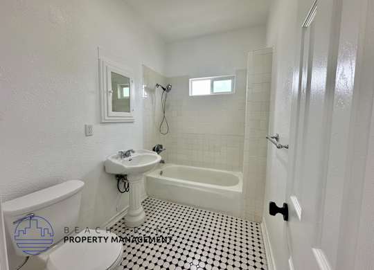 A white bathroom with a black and white checkered floor.