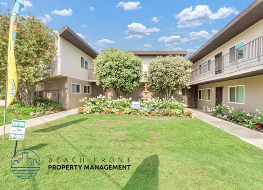 a green lawn in front of a building with trees and plants