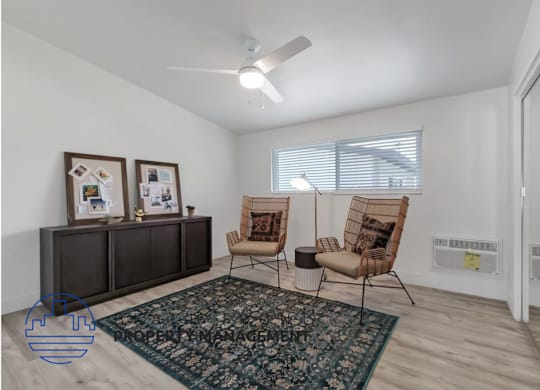 a living room with two chairs and a rug and a ceiling fan
