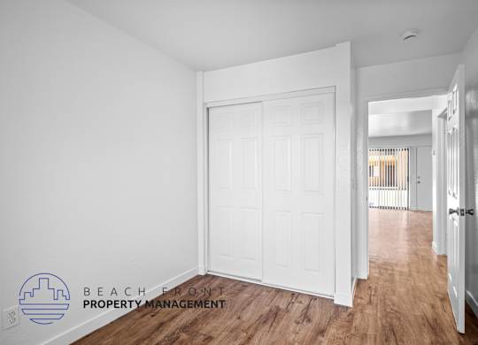 a bedroom with a white door and a hallway with a wood floor