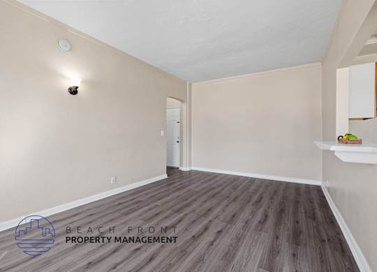 A room with wooden flooring and a logo for Beach Front Property Management.