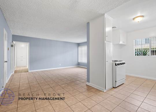 A spacious room with a refrigerator and a window with blinds.