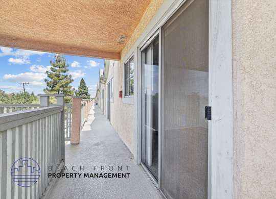 A balcony with a view of a tree and a building with a glass door.
